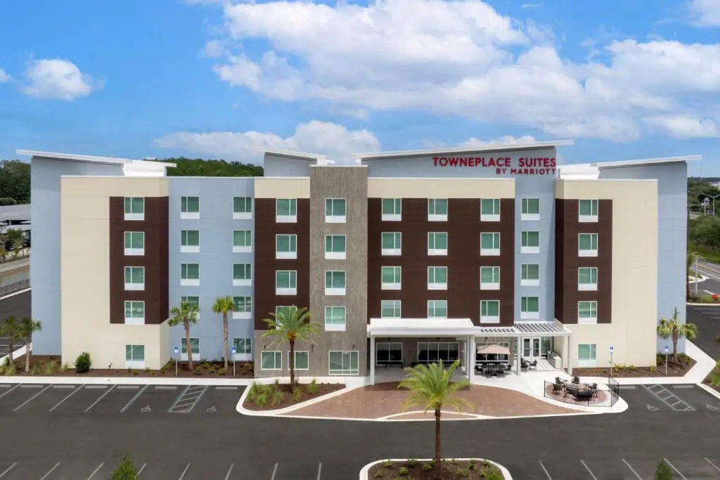 Front of the five-storey TownePlace Suites Jacksonville Airport under a blue sky, with palm trees and the parking lot in front