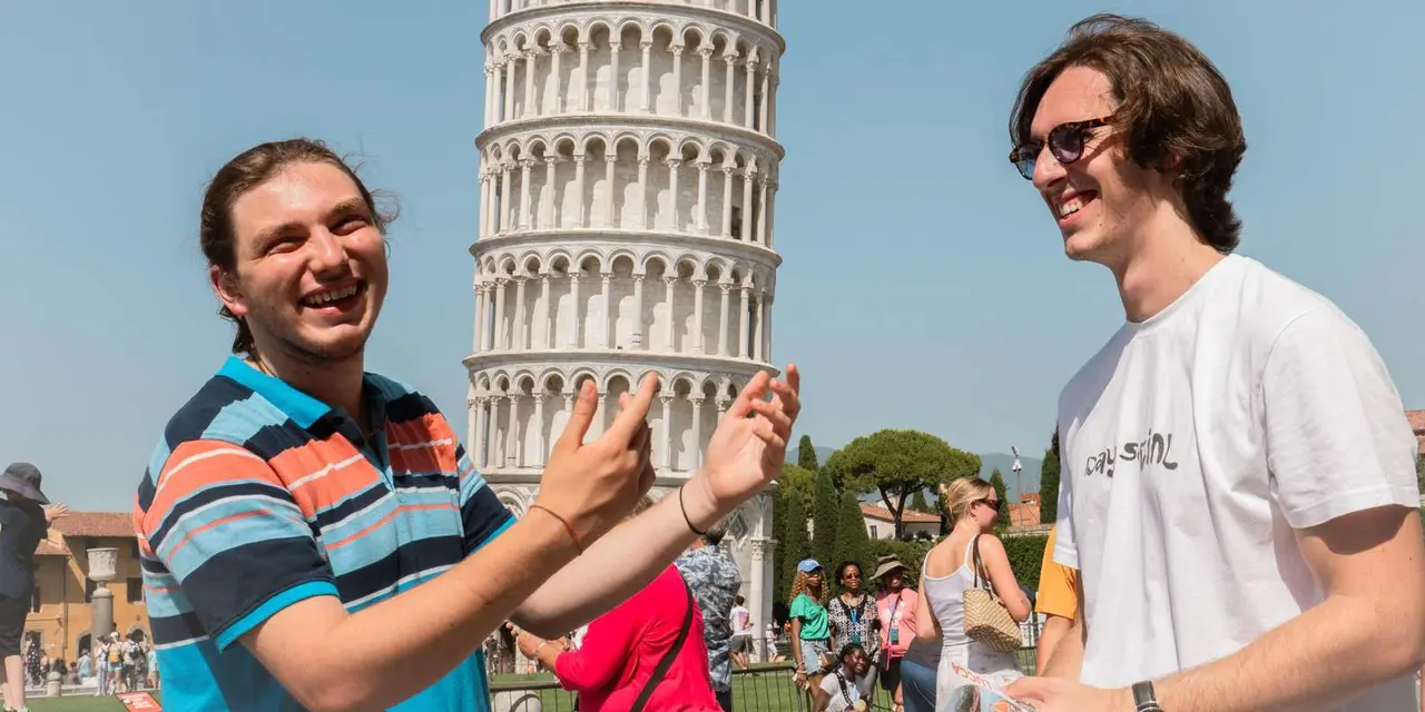 Smiling visitors posing in front of the Leaning Tower of Pisa