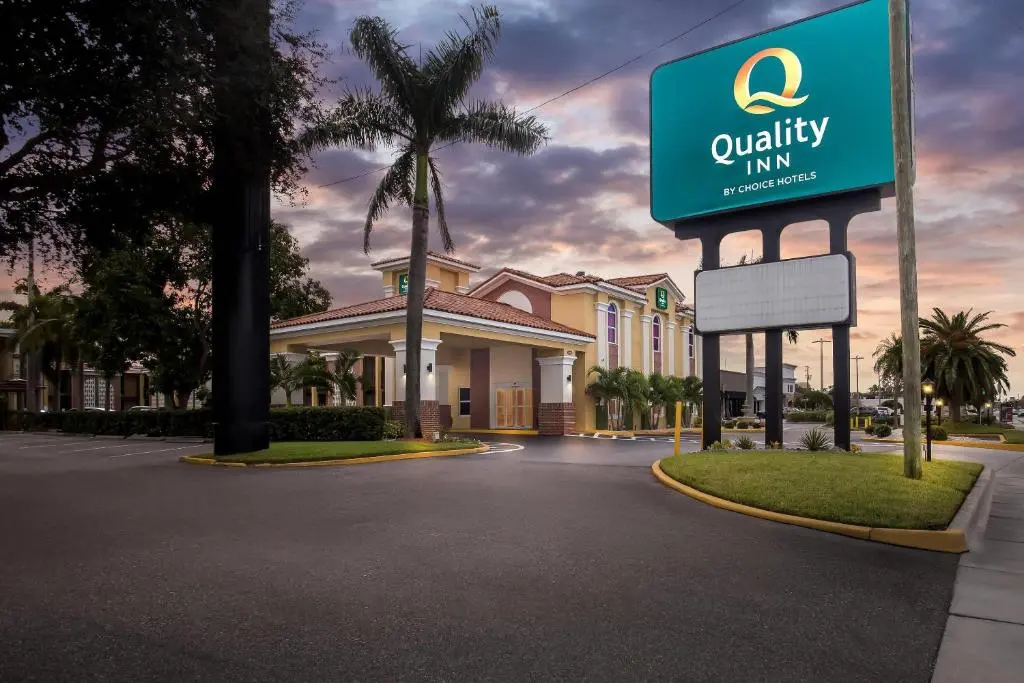 The Quality Inn sign and palm-lined entrance drive of the hotel on South Dale Mabry Highway at dusk