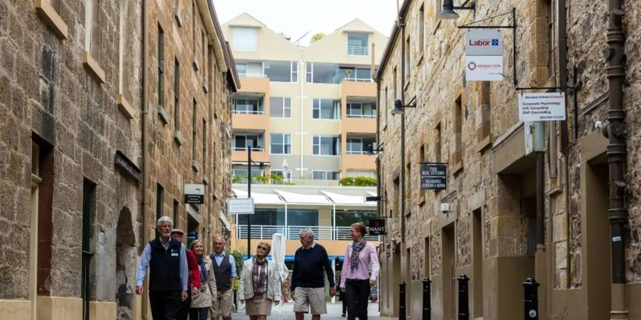 A guide leading a small group along a sandstone laneway in Hobart