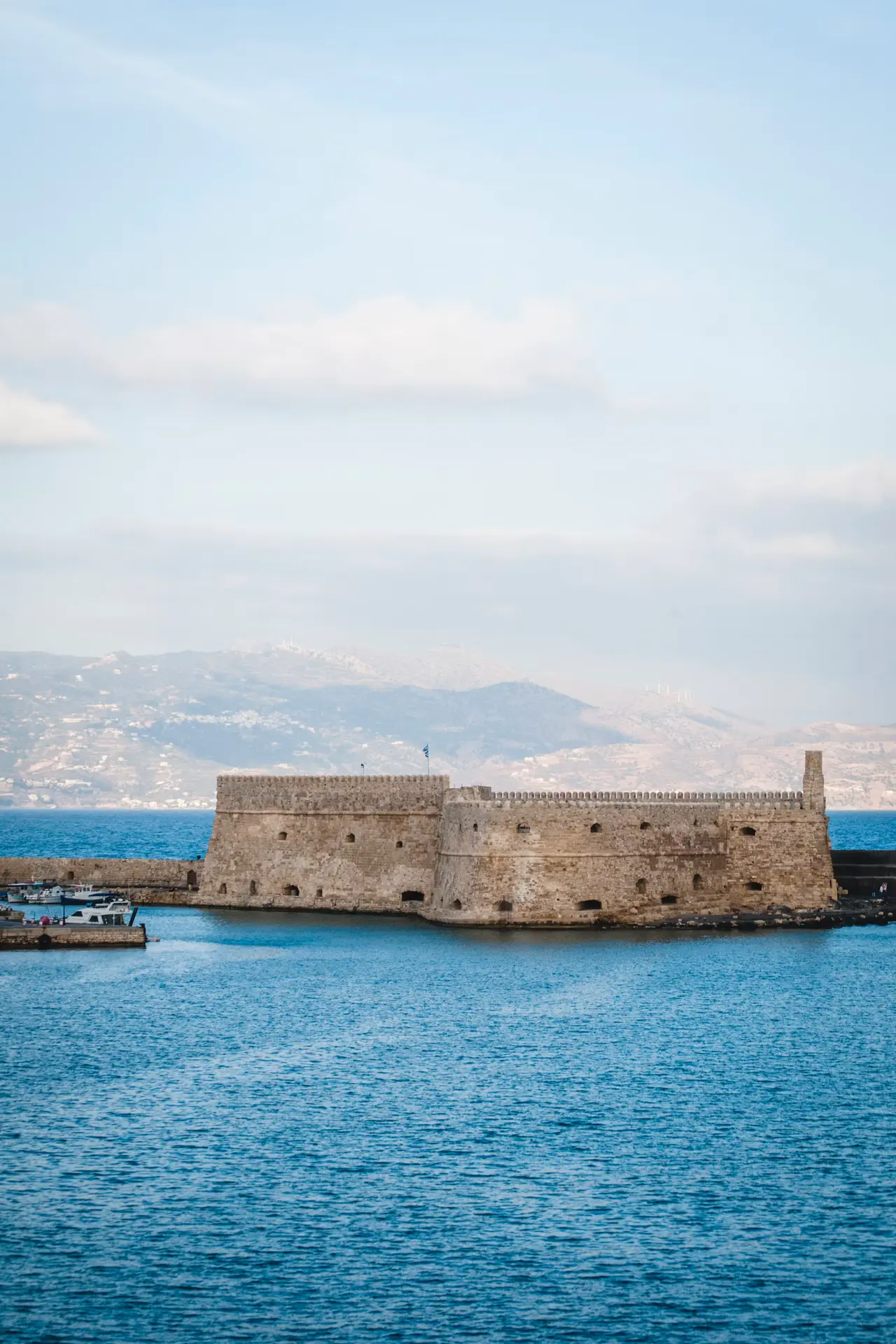 Koules, the square Venetian stone fortress at the mouth of Heraklion's old harbour, against blue sea with mountains on the horizon