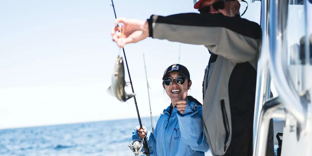 An angler holding a fishing rod on a boat deck over open water