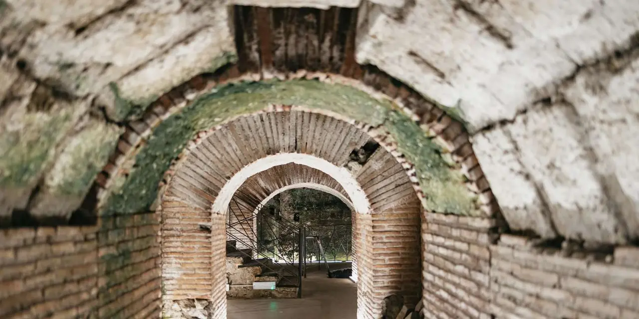A lit brick archway opening onto a vaulted underground chamber beneath Naples