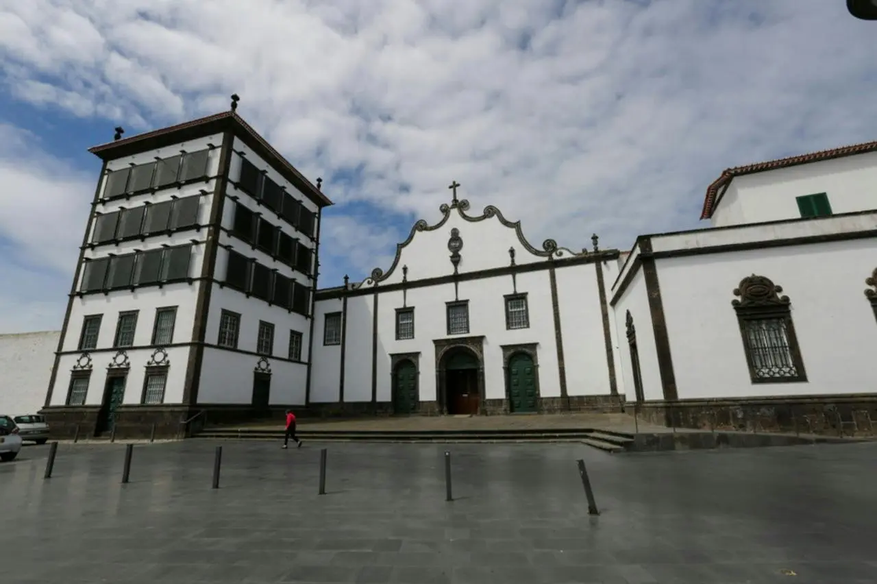 A white church façade trimmed in dark stone, on a wide paved square