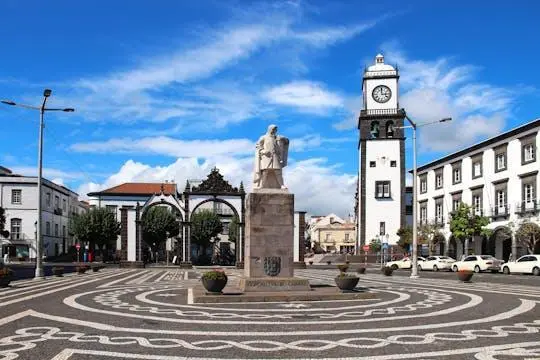 Ponta Delgada's three-arched city gates and a statue on a patterned square, a white clock tower behind