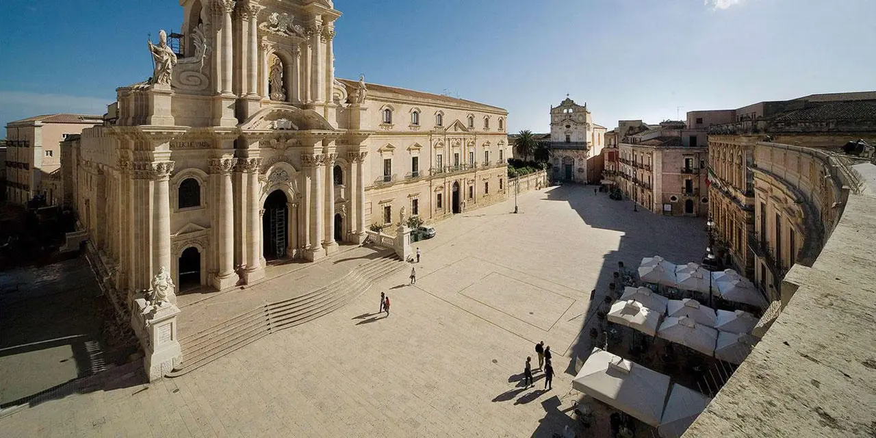 The Baroque cathedral square of Syracuse seen from above, with a few people crossing the open plaza