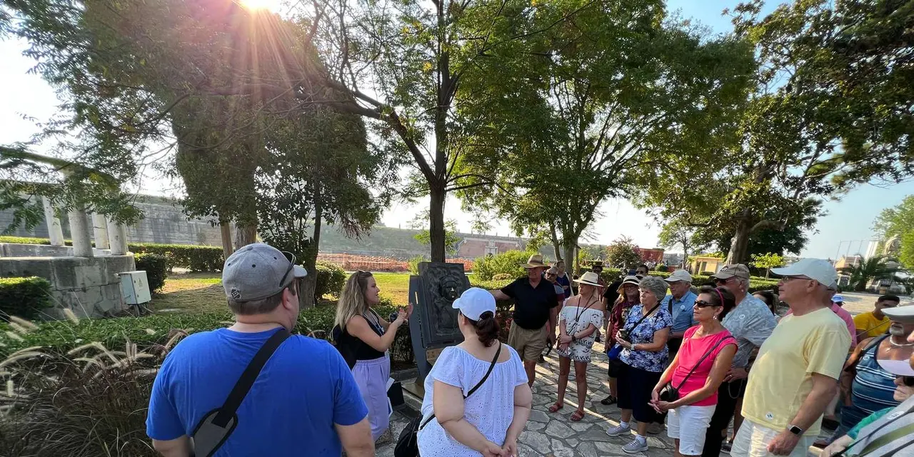 A tour group standing on a paved Old Town lane in the shade of trees