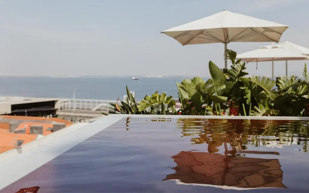 Rooftop pool at Memmo Alfama with white parasols and tropical plants, looking out over the Tagus river