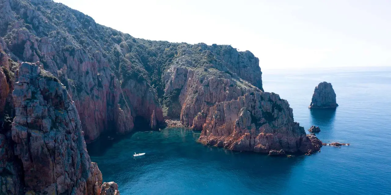 Red granite cliffs dropping into deep-blue sea on Corsica's west coast