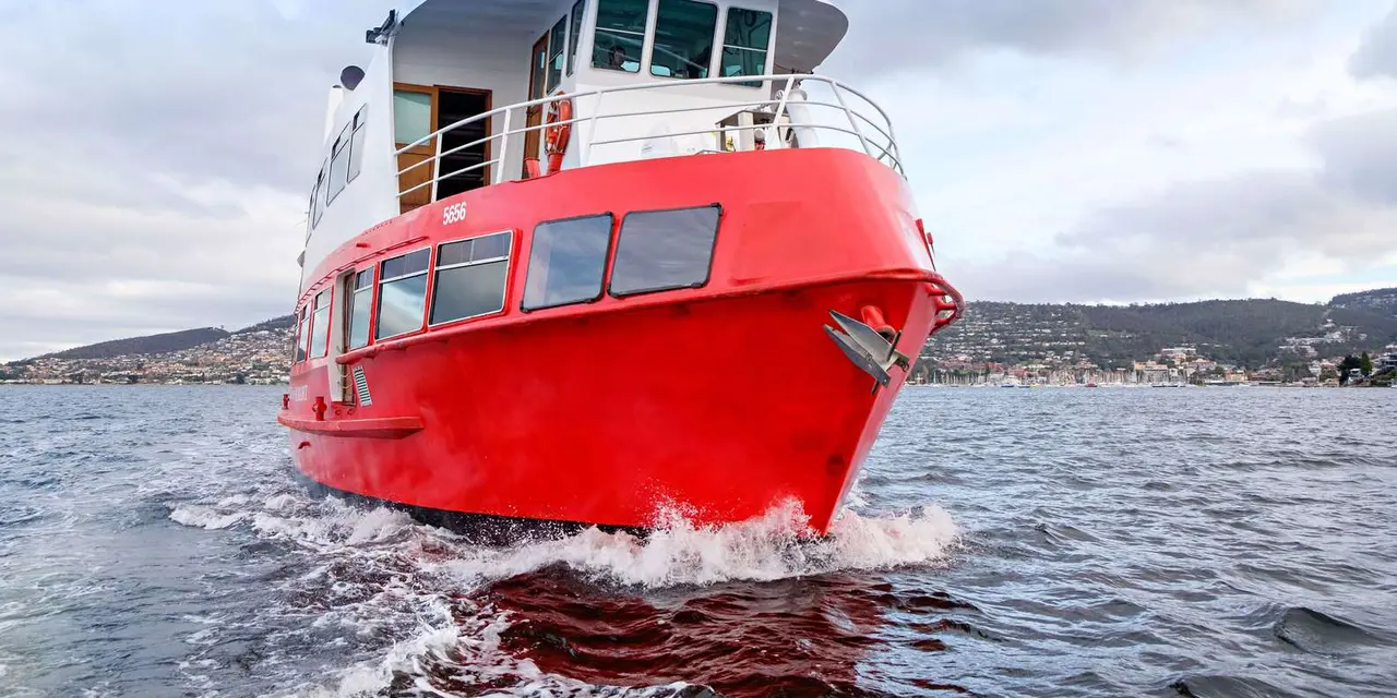 A red-and-white cruise boat moored at a Hobart pier