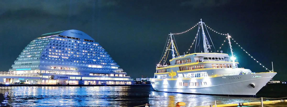 The white Concerto cruise ship lit up at night beside the ship-shaped Meriken Park Oriental Hotel