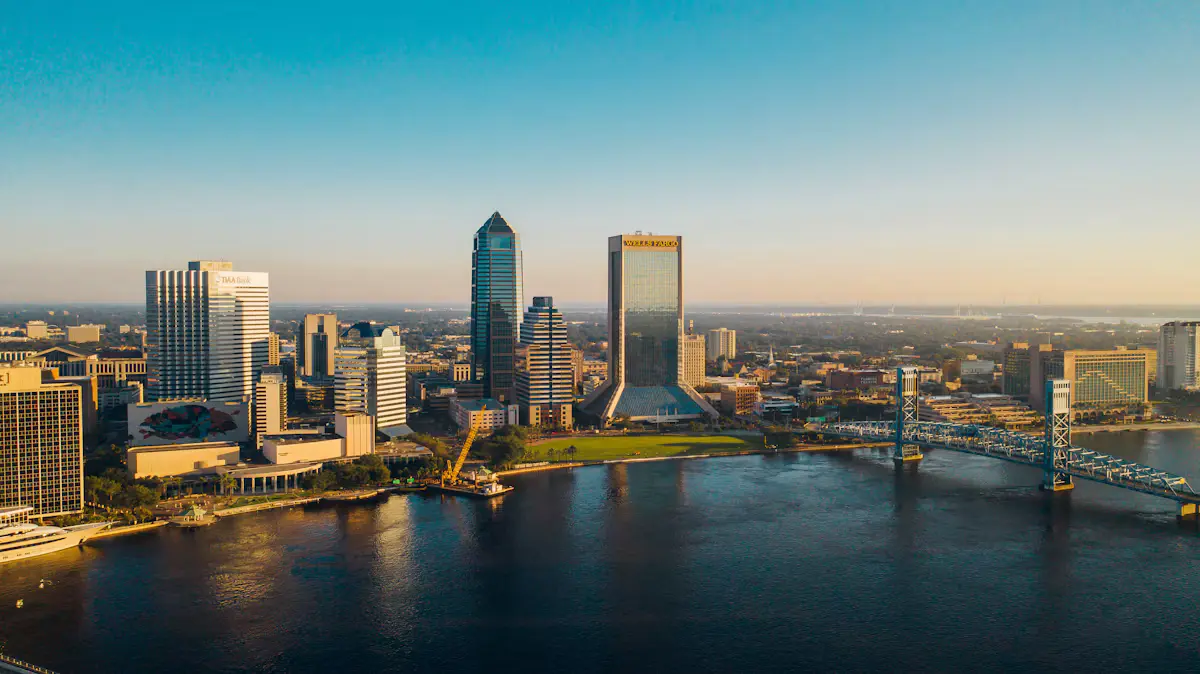 The downtown Jacksonville skyline at golden hour, seen across the St. Johns River with a blue lift bridge on the right